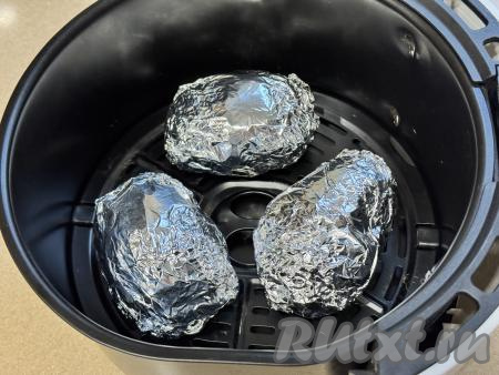 Завернуть каждую картошину в фольгу и выложить в чашу аэрогриля. Запекать картофель при температуре 200 градусов 30-40 минут. Время запекания зависит от сорта картошки. Готовность картофеля можно проверить, проткнув его прямо через фольгу зубочисткой, если зубочистка легко входит, значит картошка готова.