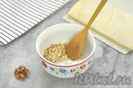Грецкие орехи рубим ножом на мелкие кусочки, перекладываем их в миску, добавляем сахар, перемешиваем и начинка для рогаликов из слоёного теста готова.