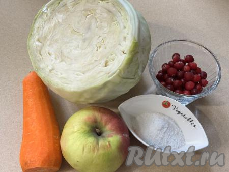 Подготовить продукты для приготовления квашеной капусты с яблоками и клюквой. Морковь почистить. Яблоко можно использовать любого сорта, его нужно вымыть. Капусту промыть водой, верхние листья снять. Клюкву можно взять как замороженную, так и свежую. Замороженные ягоды можно не размораживать. Свежую клюкву нужно промыть водой, лишнюю воду слить.