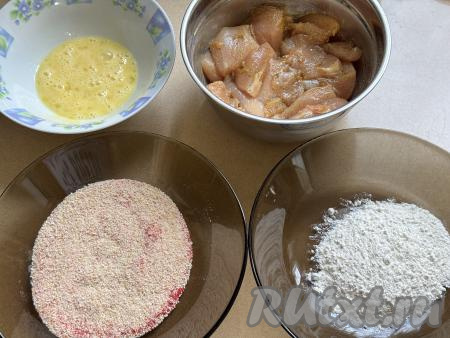 В достаточно глубокую тарелку разбить сырые яйца, взбить вилкой до однородности. Во вторую тарелку насыпать муку, а в третью - панировочные сухари. Для получения более яркого цвета в тарелку с сухарями можно добавить паприку (или карри), перемешать.