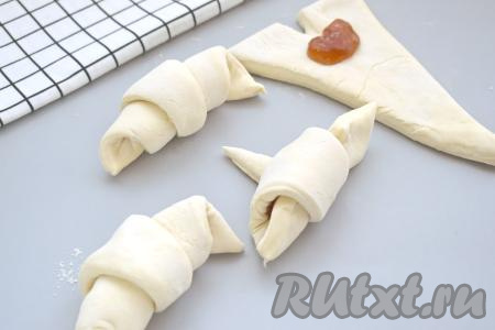 Начиная со стороны с надрезом, аккуратно сворачиваем треугольник из слоёного теста в рогалик. Хвостик получившегося рогалика должен быть снизу. Постепенно формируем все 4&nbsp; круассана с повидлом.