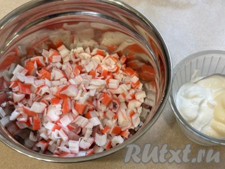 Пока картофель запекается, нужно приготовить начинку. Для этого размороженные крабовые палочки нужно освободить от слюды, мелко нарезать, выложить в миску.