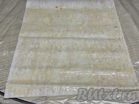 Сливочное масло растопить, дать ему немного остыть. На столе расстелить лист лаваша, смазать его растопленным маслом.&nbsp;