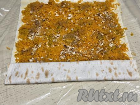 Начиная с более узкой стороны лаваша, свернуть лаваш с начинкой из тыквы в плоский рулет.&nbsp;