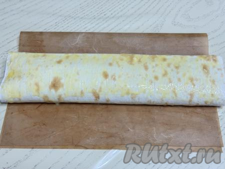 Сформированный рулет с тыквой выложить на противень, застеленный ковриком (или бумагой) для выпечки. В небольшой ёмкости яичный желток взбить вилкой до однородности, а затем получившейся смесью смазать поверхность рулета из лаваша.&nbsp;