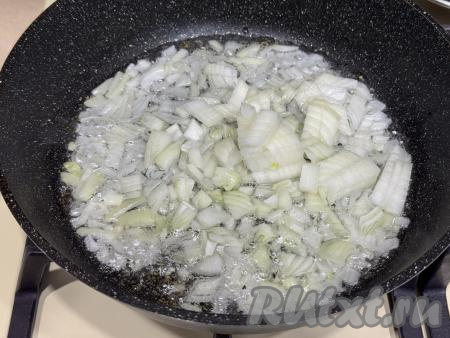 В сковороду влить растительное масло, хорошо его разогреть на огне выше среднего, выложить мелко нарезанный лук, уменьшить огонь до среднего.