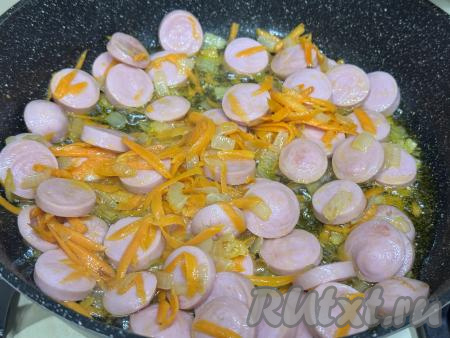 Обжарить овощи в течение 5-6 минут (до мягкости морковки), время от времени перемешивая. Затем к обжаренным овощам добавить сосиски, нарезанные на кружочки, перемешать.