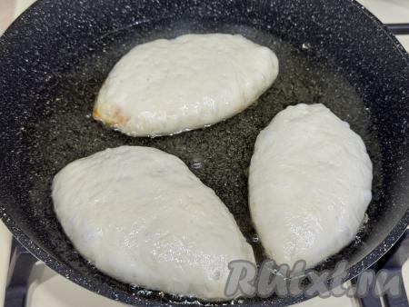 В сковороду влить растительное масло, хорошо его разогреть, уменьшить огонь до среднего. Выложить несколько пирожков швом вниз. Масло должно доходить до середины пирожков.