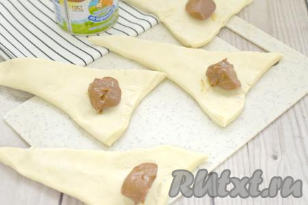 Ближе к основанию заготовок, отступая от краёв теста по 1-1,5 сантиметра, выкладываем по 1 чайной ложке варёной сгущёнки.