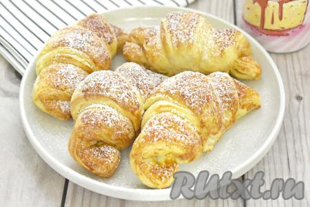 Готовые круассаны со сгущёнкой достаём из аэрогриля, выкладываем на тарелку, даём немного остыть, а перед подачей, по желанию, посыпаем сахарной пудрой.