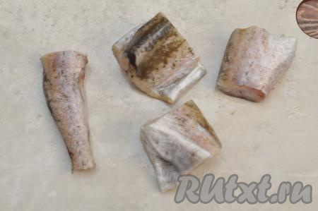 У размороженного минтая отрезать хвост с плавниками, разрезать брюшко, удалить из него внутренности вместе с чёрной плёночкой. Тщательно промыть рыбу водой. Нарезать минтая на части.