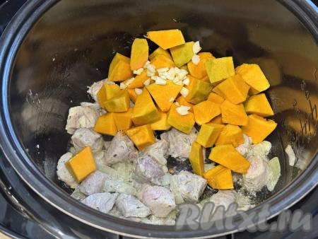 К свинине, обжаренной с тыквой, добавить кусочки тыквы и мелко нарезанный чеснок.&nbsp;