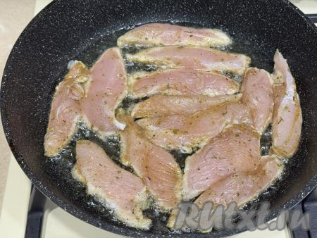 В сковороду влить растительное масло, разогреть, после этого выложить кусочки куриного филе в один слой.