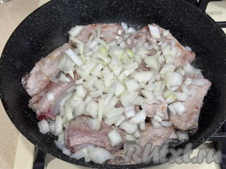 К обжаренным рёбрышкам добавить очищенный и мелко нарезанный лук, аккуратно перемешать.&nbsp;