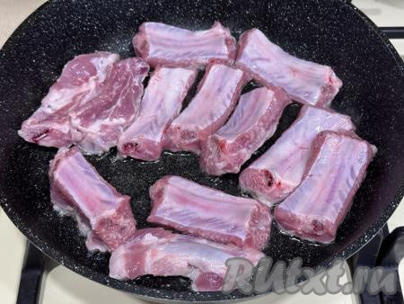 В достаточно глубокую сковороду влить растительное масло, разогреть, затем выложить свиные рёбрышки в один слой.