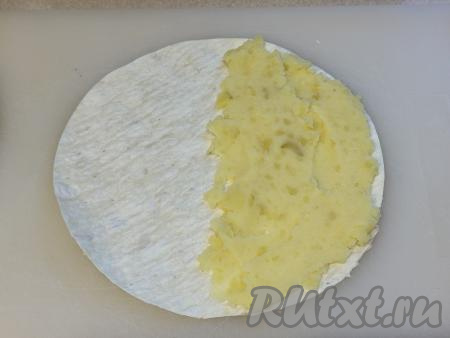 Немного отступив от краёв лаваша, на одну половину круга из лаваша выложить 2 столовых ложки картофельной начинки. Разровнять картошку, равномерно распределяя по половине лаваша, немного отступая от краёв.&nbsp;