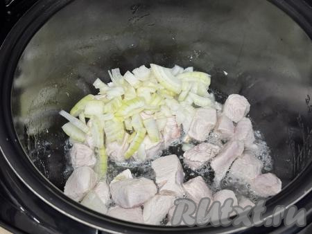Лук нарезать четверть кольцами, добавить в чашу мультиварки с обжаренным мясом, перемешать, готовить в течение 3-4 минут, иногда помешивая.