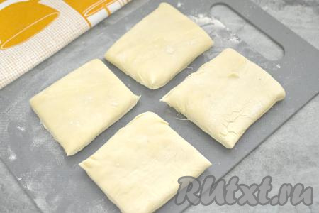 Присыпать стол мукой, выложить размороженный пласт слоёного теста, разрезать его на 4 равных части.