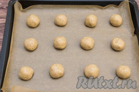 Противень застелить пекарской бумагой. Поделить овсяное тесто на 12 частей (для того чтобы было удобно делить овсяное тесто на равные части, я разделила замешанное тесто на 2 части, затем каждую часть скатала в колбаску и после этого каждую колбаску разрезала на 6 частей). Из каждой части теста скатать шарик размером примерно чуть больше, чем с грецкий орех. Выложить шарики из теста на противень на расстоянии друг от друга.