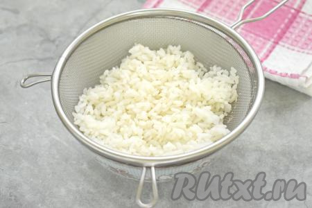 Прежде всего берём рис, выкладываем его в сито, промываем под проточной водой, после этого перекладываем в кастрюлю, в которой должно быть примерно 300 миллилитров воды, перемешиваем, ставим на сильный огонь, после закипания перемешиваем, уменьшаем огонь. Отвариваем рис до готовности (в течение минут 15-20, рисинки должны стать мягкими). Сварившийся рис откидываем на сито, немного промываем под холодной проточной водой. Оставляем рис в сите, чтобы он остыл и стекла вся вода.