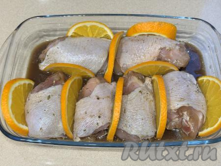 Выложить куриные бёдра в жаропрочную форму, залить их апельсиновым маринадом, в котором они мариновались, вставить полукружочки апельсина между бёдрышками.&nbsp;