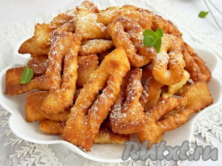 Воздушный, аппетитный хворост, приготовленный из теста, замешанного на молоке и дрожжах, после остывания посыпать сахарной пудрой и подать вкусную, пышную выпечку к чаю.