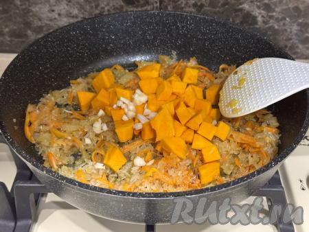 К рису, обжаренному с овощами, добавить мелко нарезанный чеснок и тыкву, нарезанную на кубики с размером стороны 1 сантиметр,&nbsp;соль и специи по вкусу,&nbsp;перемешать овощи.&nbsp;