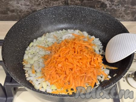 После того как лук обжарится до прозрачности, выложить в сковороду натёртую на крупной тёрке морковь, перемешать овощи.