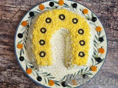 Маслины нарезать на тонкие кружочки и выложить сверху, формируя как бы отверстия для гвоздей на подкове.&nbsp;Украсить салат "Подкова на счастье" на свое усмотрение. Я разложила половинки маслин и кружочки из отварной морковки по кругу тарелки. Блюдо не требует пропитки, его можно сразу подавать к столу.