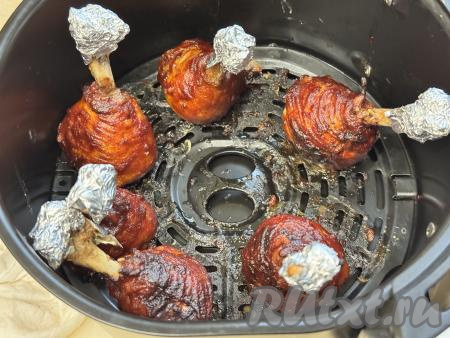 Готовые куриные чупа-чупсы должны хорошо подрумяниться. Куриные ножки должны быть уже готовы. Для того чтобы проверить готовность, проткните ножку в самой толстой части зубочисткой, если вытекает прозрачный сок без примесей крови, значит мясо готово. В зависимости от мощности аэрогриля для запекания может потребоваться чуть больше или чуть меньше времени, ориентируйтесь по готовности голеней. Мощность моего аэрогриля 1350 Ватт.