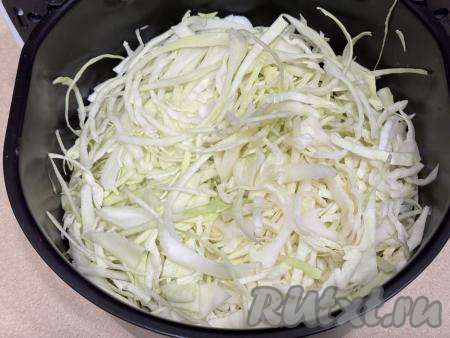 Капусту промыть водой, удаляя верхние листья. Нарезать капусту на тонкие полоски. Из чаши аэрогриля убрать решётку. Выложить нарезанную капусту в чашу аэрогриля.