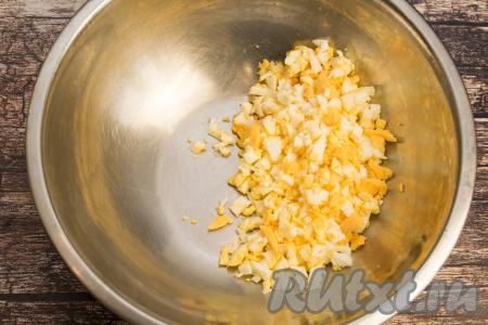 Сварившиеся яйца и картошку полностью остудить. Зелёный лук промыть водой, обсушить. Яйца очистить, нарезать на мелкие кубики. Традиционно ингредиенты для "Оливье" желательно нарезать на кубики, размер которых будет примерно равен размеру горошка, тогда салат получится особенно вкусным и нежным, да и придавать салату форму лошади будет достаточно просто. Нарезанные яйца выложить в глубокую миску.