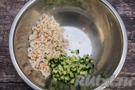 Оставшиеся белые части крабовых палочек нарезать на мелкие кусочки, сложить в глубокую миску. Огурец вымыть, отрезать кончики с двух сторон. Огурчик тоже нарезать на мелкие кубики, добавить в миску с крабовыми палочками.