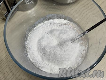 Затем всыпать в миску соль и грамм 200 просеянной муки, перемешать тесто столовой ложкой.