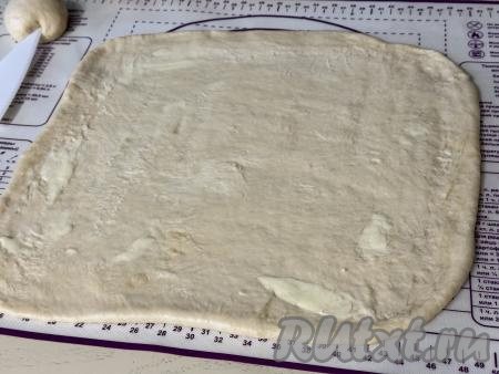От теста отрезать небольшой кусочек для украшения. Остальное тесто раскатать в квадратный пласт толщиной примерно 3-4 миллиметра, смазать всю поверхность теста 50 граммами сливочного масла комнатной температуры.