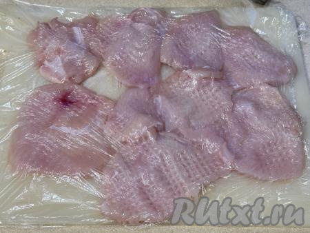 Куриное филе нарезать на пласты толщиной 1 сантиметр, накрыть пищевой плёнкой и отбить до толщины примерно 5-7 миллиметров.&nbsp;