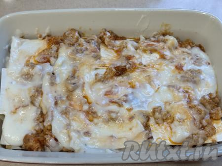 Выложить в один слой немного внахлёст листы лапши для бешбармака, таким образом, чередуя слои (часть мясной начинки, часть соуса, часть натёртого сыра), сформировать лазанью.