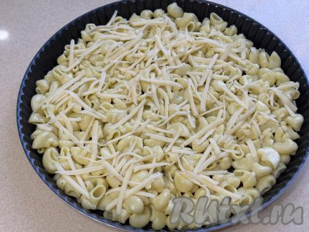 Сыр натереть на крупной тёрке. Небольшим количеством натёртого сыра посыпать макароны (остальной сыр нам потребуется позже).