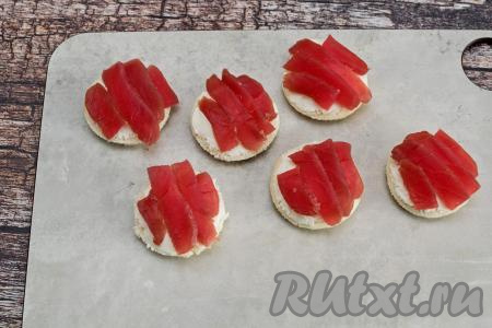 На сыр выложить тонко нарезанное филе красной рыбы.