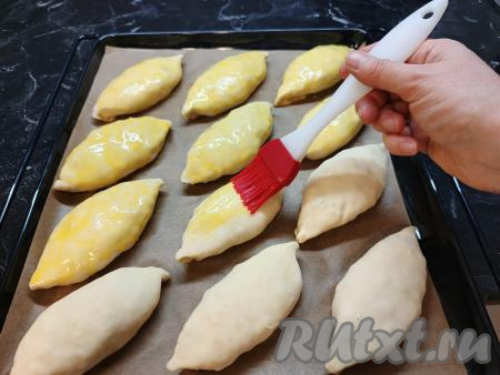 Выложить сформированные пирожки швом вниз на противень, застеленный пекарской бумагой. У меня все пирожки не уместились на противень, поэтому я выпекала в духовке их в несколько заходов. Для того чтобы готовые пирожки были покрыты приятной, золотистой корочкой, непосредственно перед закладыванием в духовку пирожки нужно смазать смесью из желтка и молока. Выпекать пирожки с капустой в духовке, заранее разогретой до 180 градусов, минут 30.​​​​​​