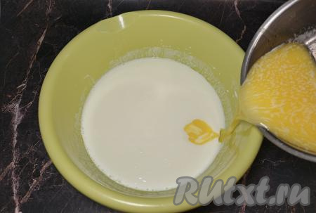 Пока капуста остывает, займёмся замешиванием бездрожжевого теста для пирожков. Сливочное масло растопить (растопить масло можно в микроволновке или на плите), дать немного остыть. Пока жарилась капуста, кефир согрелся, вошёл в реакцию с содой, поэтому его поверхность запенилась. В миску с кефиром влить растопленное негорячее сливочное масло, перемешать столовой ложкой до однородности.