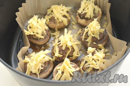 Фаршированные грибы посыпаем сыром, натёртым на крупной тёрке. Чашу возвращаем в аэрогриль, готовим шампиньоны, фаршированные фаршем и сыром, оставшиеся 5 минут. Сыр за это время расплавится, образуя аппетитную корочку.