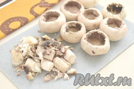 Аккуратно «выкручиваем» из шампиньонов ножки. С помощью чайной ложки извлекаем грибную мякоть из шляпок шампиньонов, не повреждая стенки.