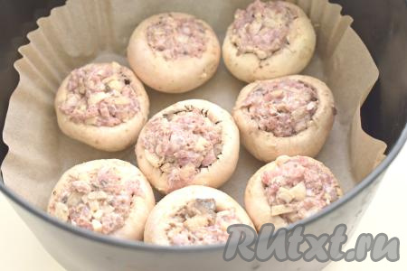 Чашу аэрогриля застилаем пергаментом, выкладываем шампиньоны, фаршированные фаршем.