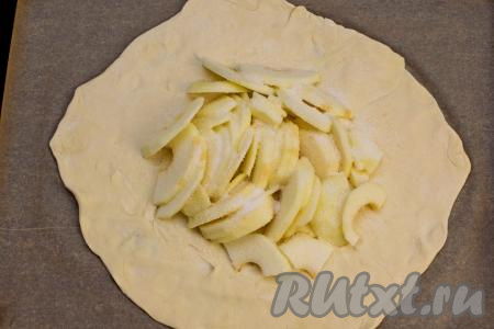 Выложить кусочки яблок в середину теста, отступая от краёв теста по 3-5 сантиметров. Присыпать яблоки сверху 3 чайными ложками сахара.