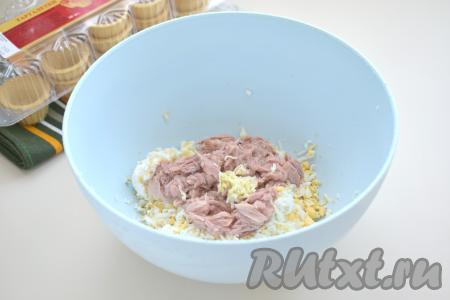 Открываем банку с консервированным тунцом (у меня - тунец рубленый в собственном соку). В миску с сыром и яйцом добавляем кусочки консервированного тунца без жидкости и пропущенный через пресс (или натёртый на мелкой тёрке) зубчик чеснока.