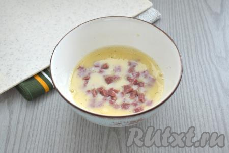 В получившуюся омлетную массу добавляем колбасу, нарезанную на мелкие кубики, перемешиваем столовой ложкой.