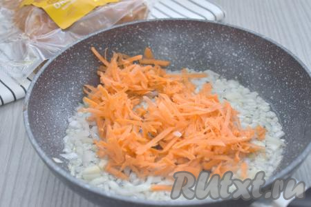 К обжаренному луку выкладываем морковку, натёртую на крупной тёрке, сразу перемешиваем овощи, обжариваем их 4-5 минут, время от времени помешивая.