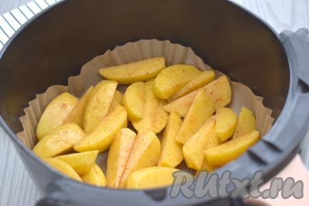 Чашу аэрогриля застилаем пергаментом. Выкладываем в чашу подготовленную картошку. Отправляем чашу в аэрогриль.