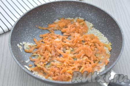 К обжаренному луку добавляем морковку, натёртую на крупной тёрке, перемешиваем. Обжариваем овощи, иногда помешивая, до мягкости моркови (в течение минут 5), затем убираем с огня.